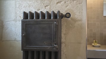 Radiador en una habitación con pared de azulejos y encimera con una botella y un cuenco.