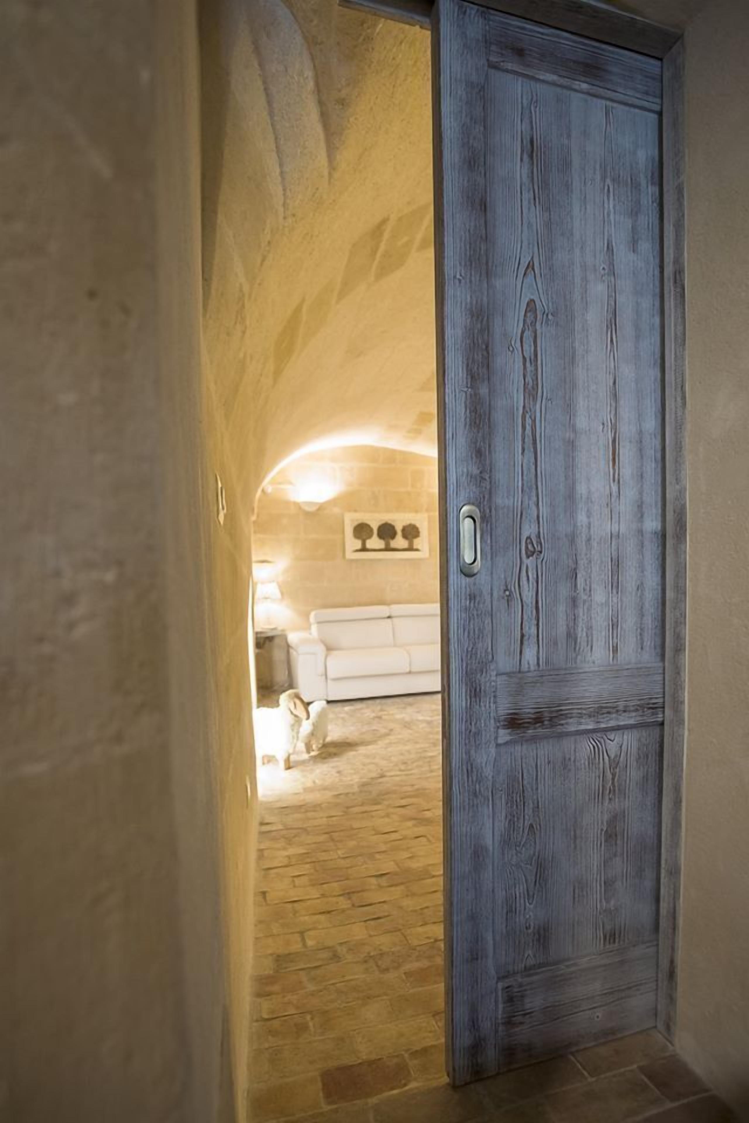 A hallway leading to a room with a stone floor and a white sofa.