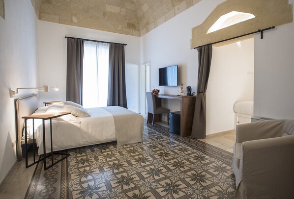A hotel room with a bed, desk, chair, and a television. - Palazzo Montemurro (Matera)