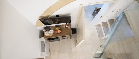 A modern kitchen with a wooden table, a built-in oven, and a glass railing overlooking a balcony.