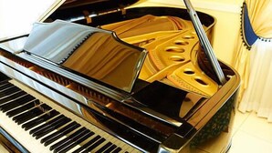 Un piano à queue au vernis brillant, avec un intérieur noir et doré.