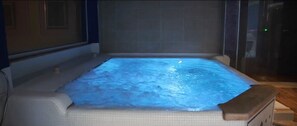 Un jacuzzi con revestimiento de azulejos y cerramiento de vidrio.