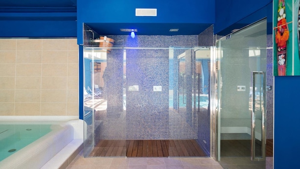 Une salle de bain moderne avec une douche à parois de verre, un plancher en bois et une baignoire visible.