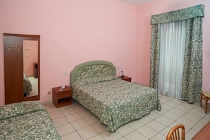 Un dormitorio con cama, mesita de noche, espejo, armario y ventana con cortinas.