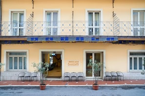 Un hotel con fachada amarilla, un balcón con barandas metálicas y un letrero que dice 'Hotel Cavallotti'.