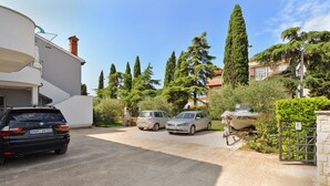 A residential area with a paved driveway, parked cars, and a boat. - Apartment 1701/17572 (Istria - Fažana), 300m from the beach (Fažana)