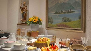 Un bufé de desayuno con diversos alimentos, una estatua, un cuadro y un jarrón con flores.