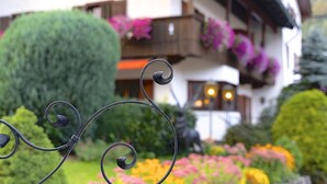 Un jardín con una estructura metálica en espiral, un seto bien cuidado y flores coloridas.