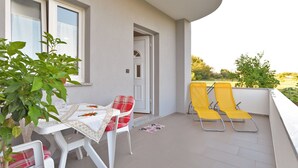 A balcony with a table and chairs, a door, and a view of greenery. - Apartment 1701/17690 (Istria - Fažana), 300m from the beach (Fažana)