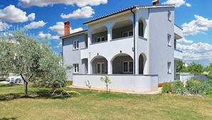 A two-story building with a balcony, arched windows, and a chimney.