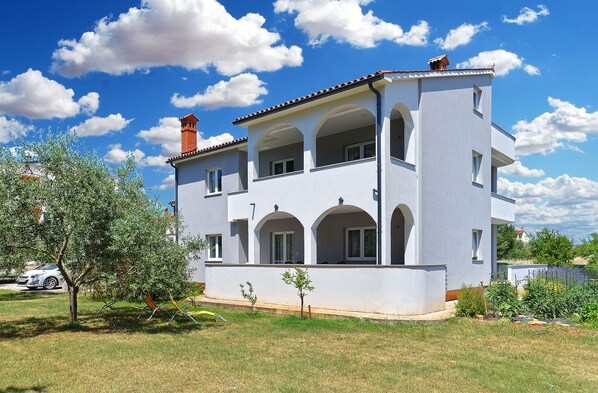 A two-story building with a balcony, arched windows, and a chimney.