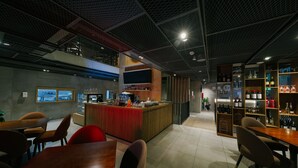 A modern bar area with a counter, seating, and a wine display.