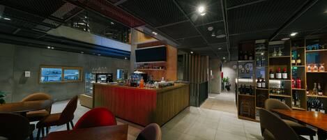 Zona de bar moderna con barra, asientos y una exhibición de vinos.