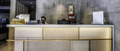 A reception desk with a modern design, featuring a patterned metal partition and a digital display.