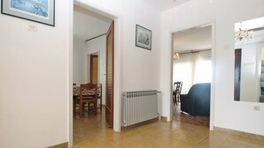 A hallway with a dining area, a radiator, and a blue sofa.