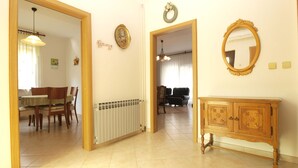 A spacious living area with a dining table, chairs, a radiator, a wooden cabinet, and a mirror.