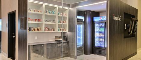 A modern retail space with a glass-fronted snack display and a refrigerated beverage area.
