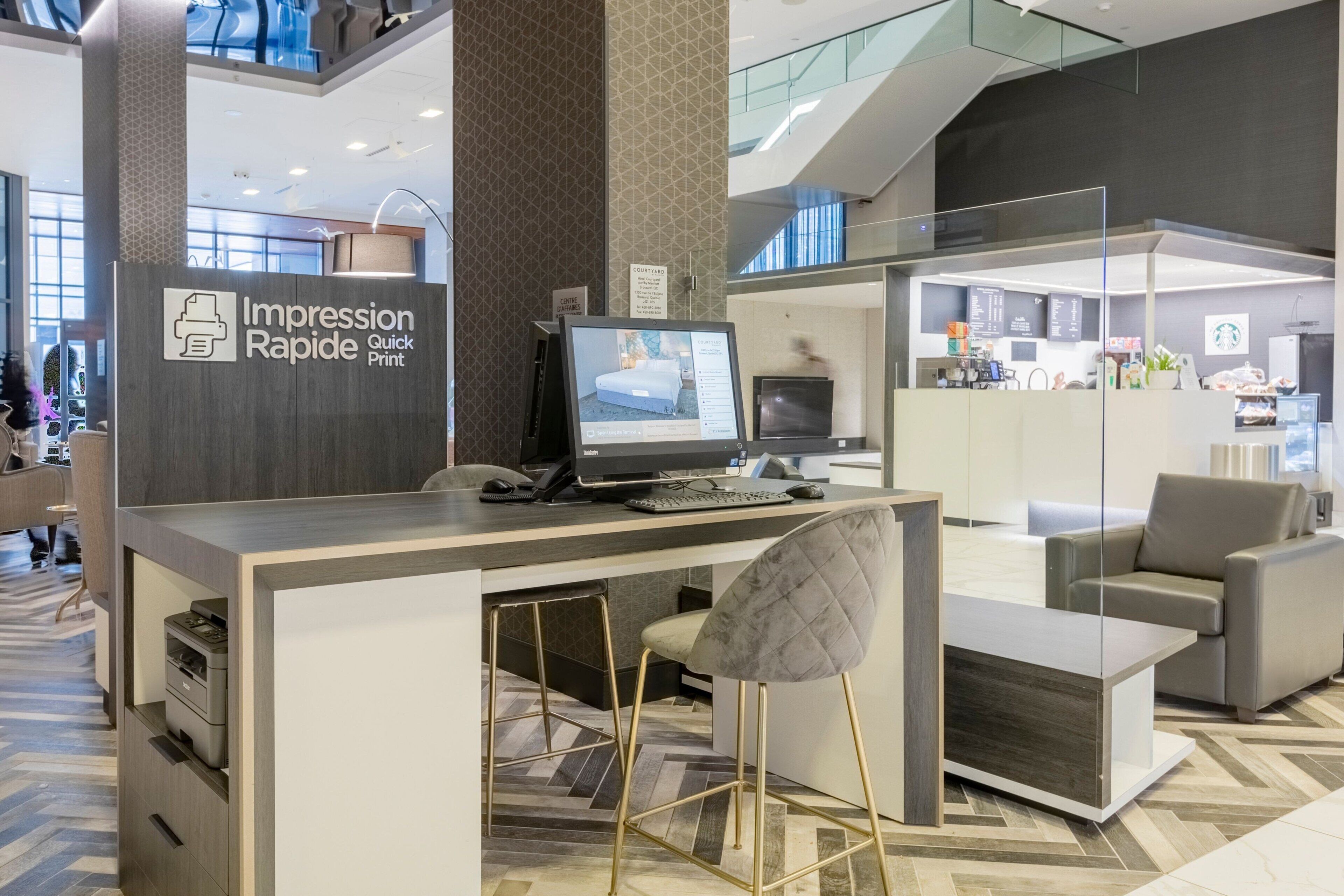 A modern hotel lobby with a reception desk, seating area, and a Starbucks counter.