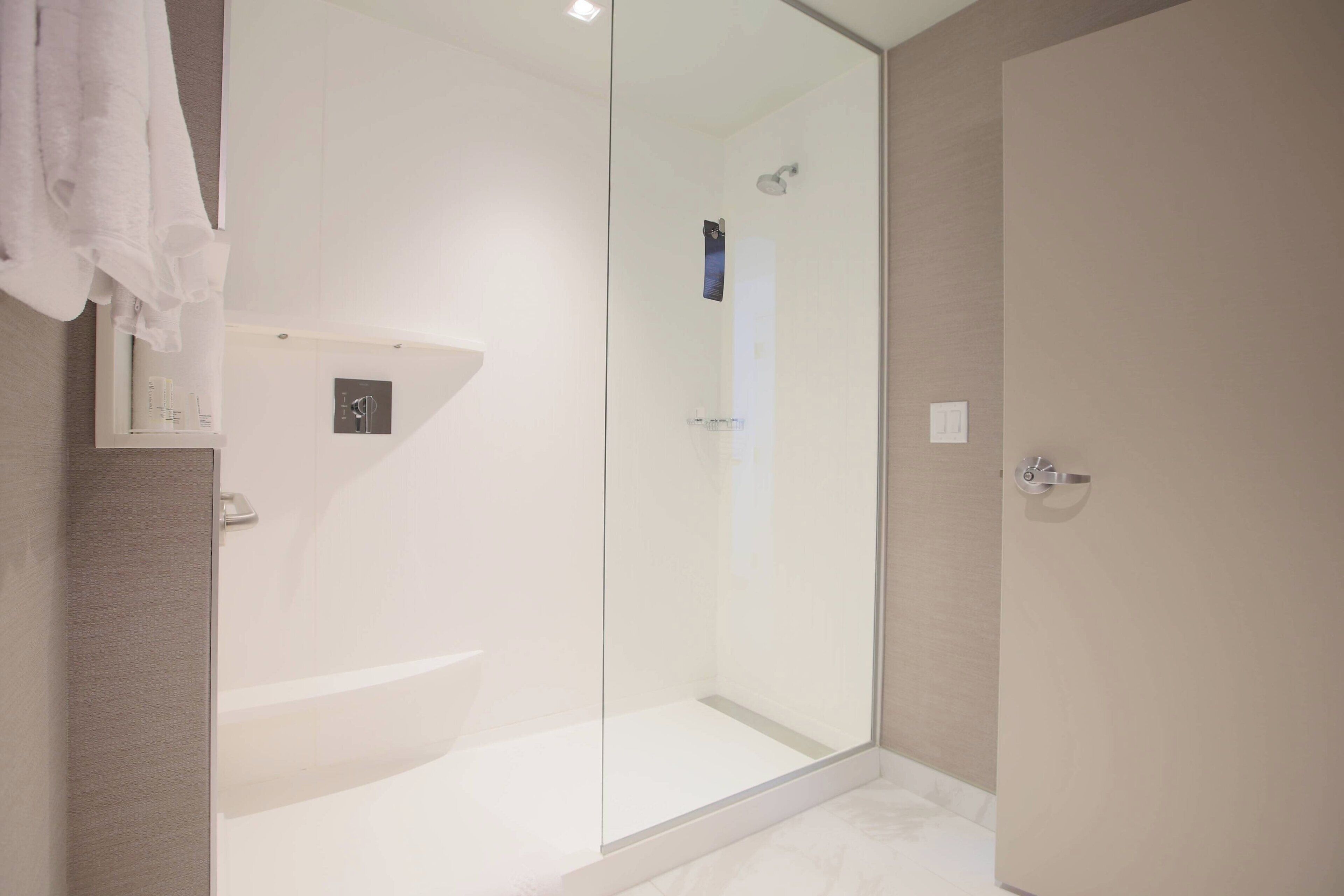 Een moderne badkamer met een douchecabine van glas, een witte badkuip en een handdoekrek.