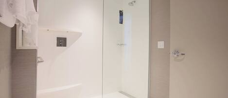 A modern bathroom with a glass-enclosed shower, a white bathtub, and a towel rack.