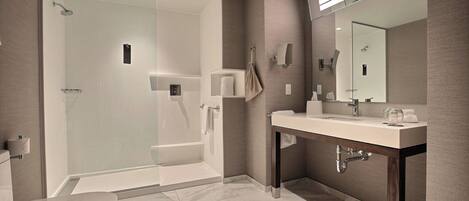 A modern bathroom with a glass-enclosed shower, a vanity with a mirror, and a toilet.