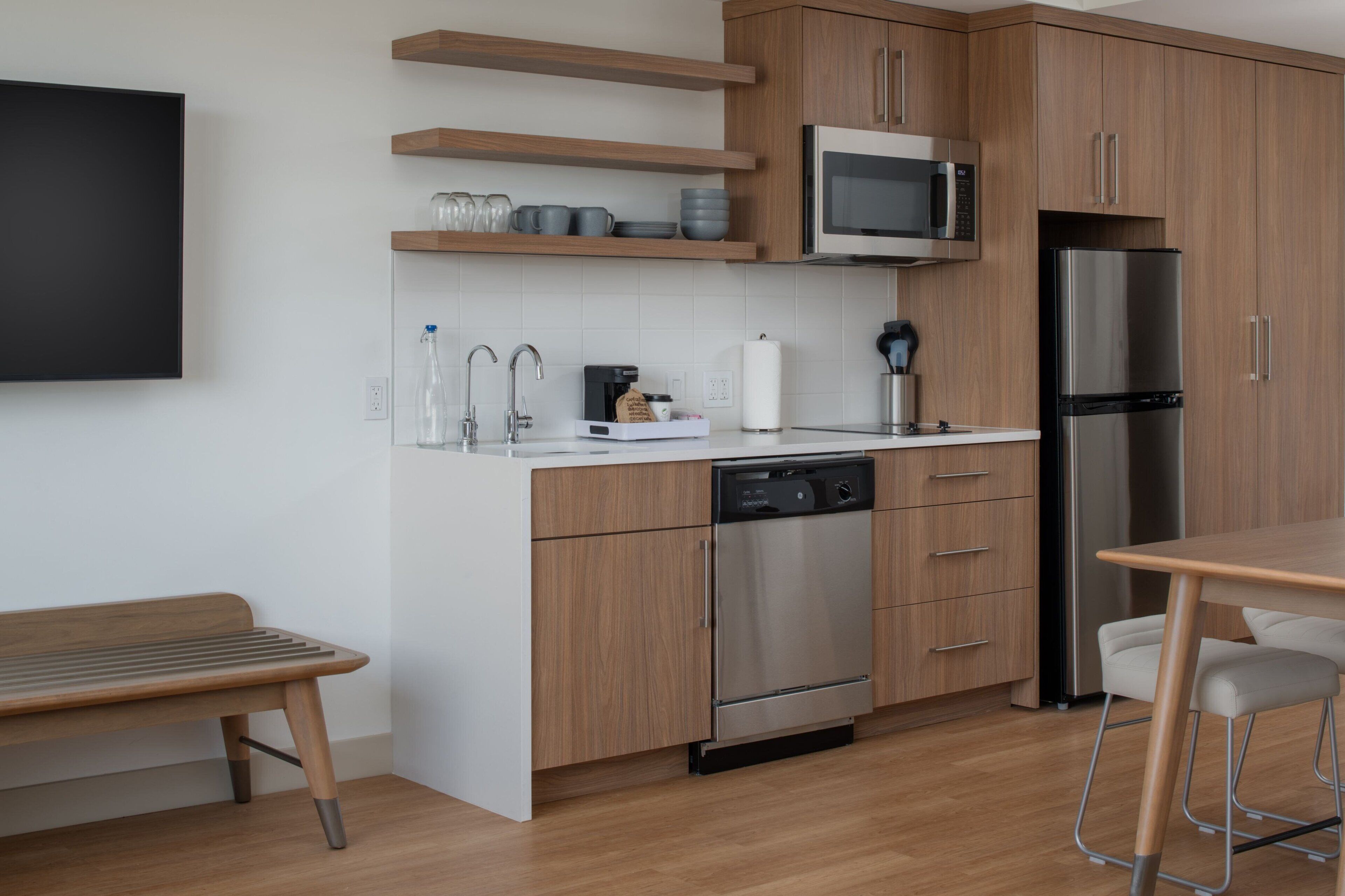A modern kitchen with wooden cabinets, a stainless steel refrigerator, a microwave, and a dishwasher.