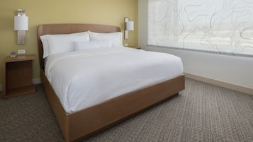A hotel room with a large bed, two bedside tables, a nightstand, and a window with a view.