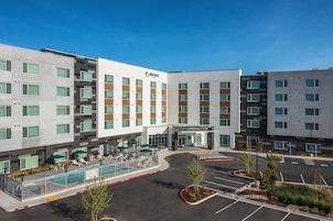 Un hotel moderno con piscina, zona de estar exterior y aparcamiento.