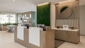 A modern reception desk with a green vertical garden, a circular logo, and a sign indicating 'Marriott Bonvoy'. - Element by Marriott San Jose Milpitas (Milpitas)