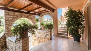 A covered outdoor area with stone arches, potted plants, and a staircase leading to a higher level. - Apartment 1706/17820 (Istria - Liznjan), 1250m from the beach (Liznjan)