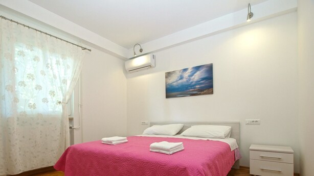 A bedroom with a bed, a nightstand, a wall-mounted air conditioner, and a painting of a beach scene. - Apartment 1707/17625 (Istria - Banjole), 100m from the beach (Banjole)