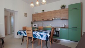 A compact kitchen with wooden cabinets, a dining table with chairs, and a green refrigerator. - Apartment 1707/17625 (Istria - Banjole), 100m from the beach (Banjole)