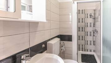 Een moderne badkamer met douche, toilet en wastafel.