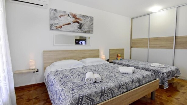 Ein Hotelzimmer mit zwei Betten, einem Holz-Kopfteil, einem Bild an der Wand, einem Spiegel und einem Kleiderschrank.