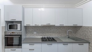 Eine moderne Küche mit weißen Schränken, einer Mikrowelle, einem Backofen, einem Gasherd und einem Spülbecken.