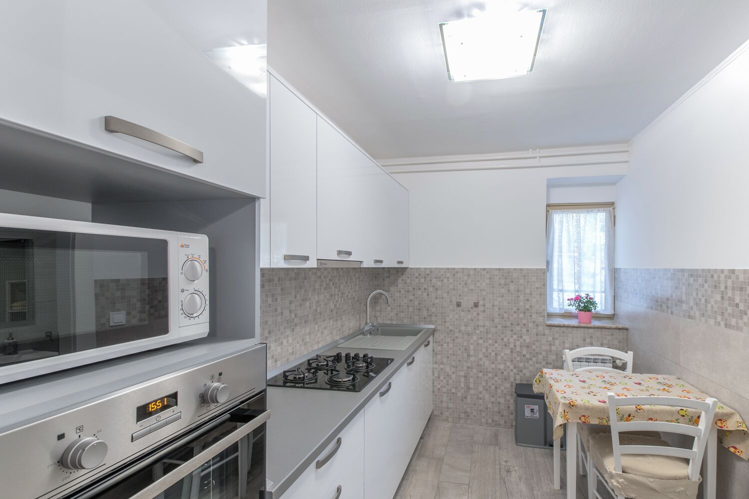 Una cocina compacta con microondas, estufa y horno. Hay una ventana pequeña con vistas al exterior.