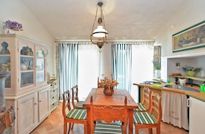Enjoy meals in this dining area with a wooden table and six comfortable chairs, surrounded by a large window and a beautiful painting.
