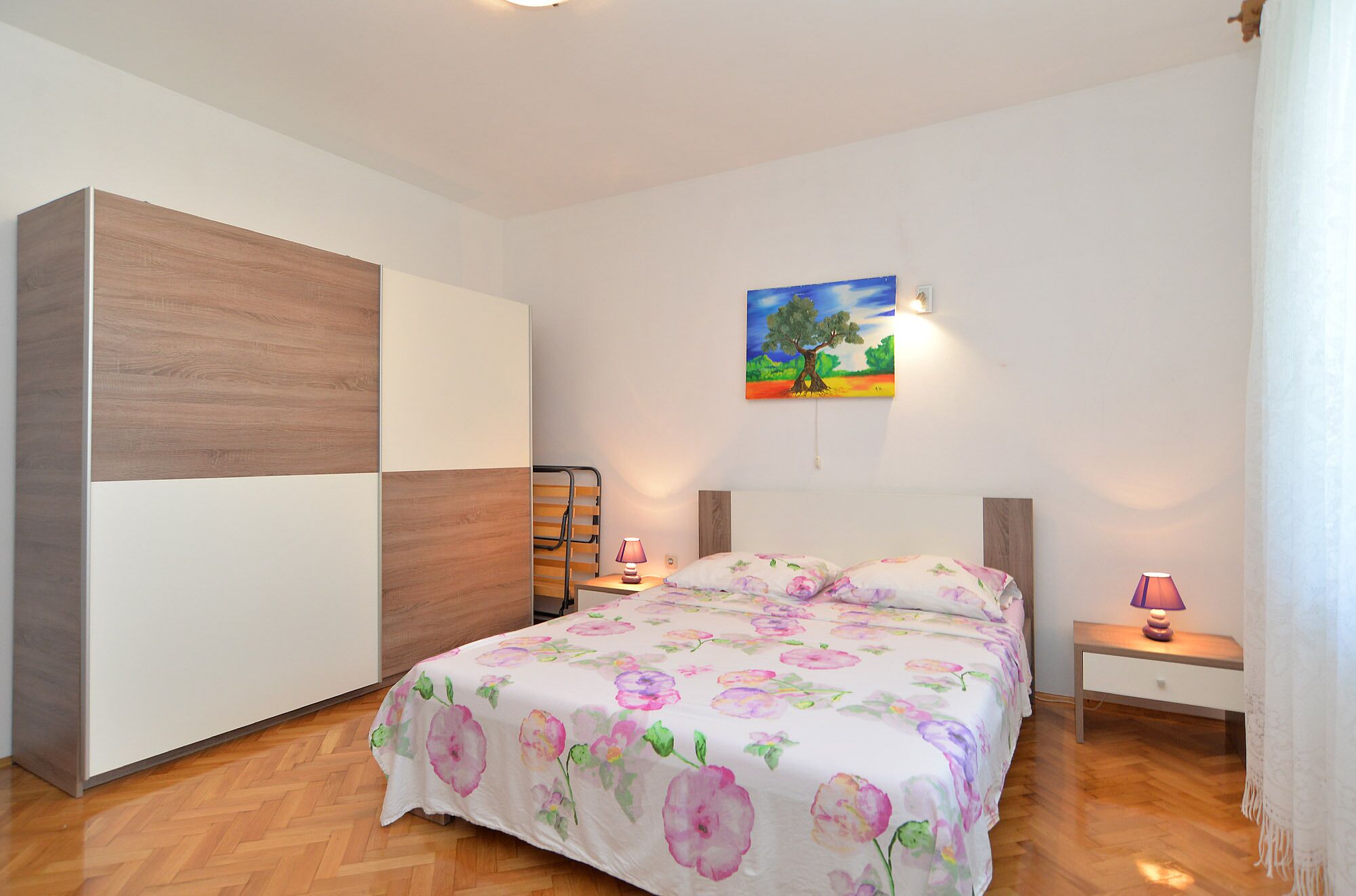 Une chambre à coucher avec un lit, des tables de chevet, un tableau et une armoire.