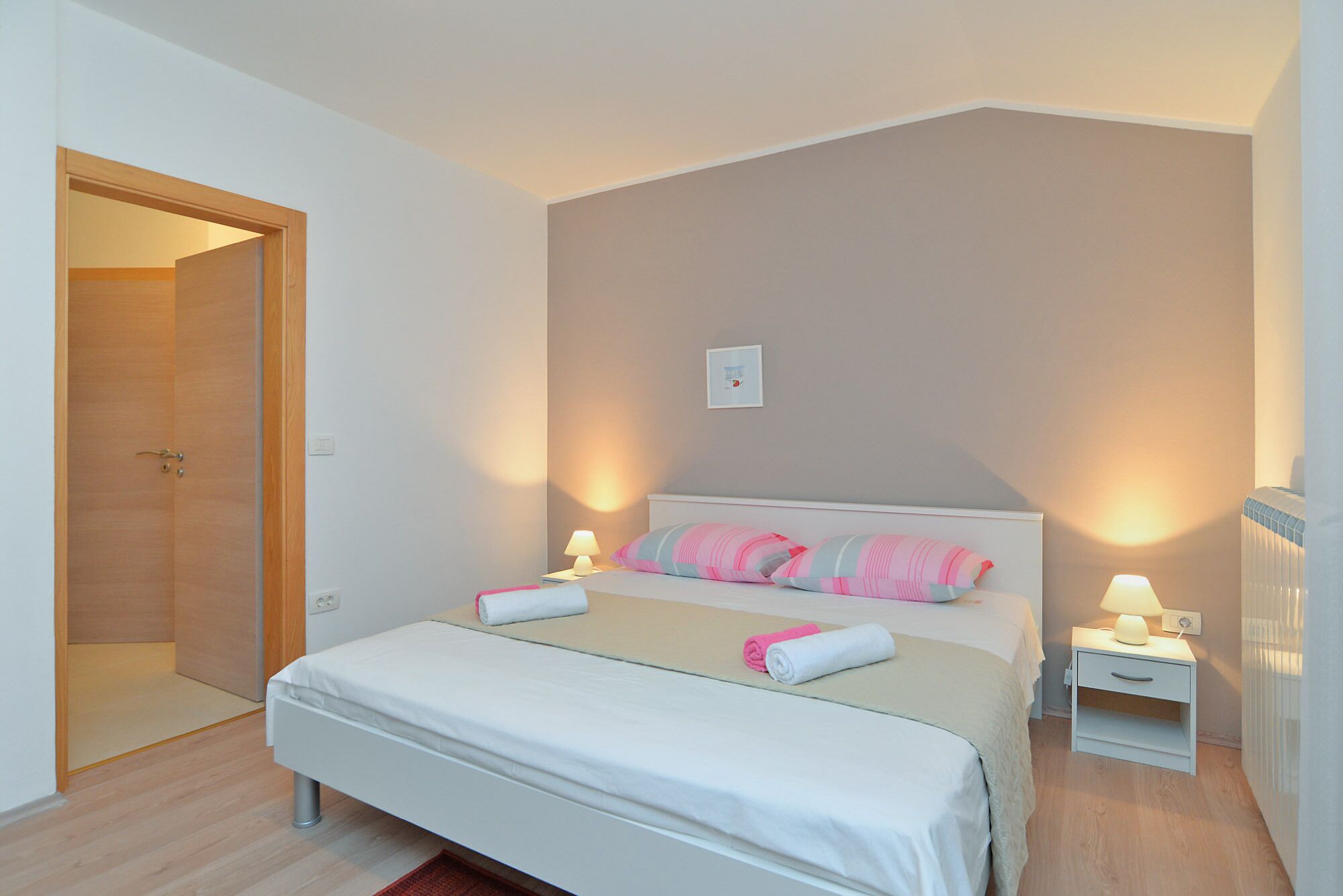 A bedroom with a bed, bedside tables, and a door.