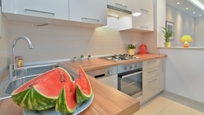 Una cocina moderna con un fregadero, estufa, horno y una encimera con un plato de sandía.