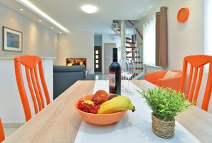 A dining area with a table set for two, featuring a bowl of fruit, a bottle of wine, and a potted plant. - Apartment 1726/17901 (Istria - Pula), 2000m from the beach (Pula)