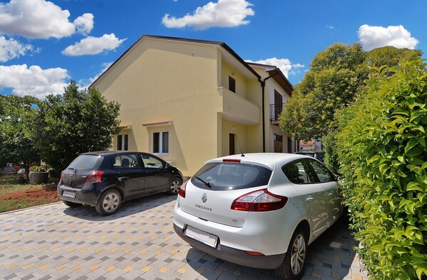 A two-story building with a yellow facade and a red roof. There are two cars parked in front, one black and one white. - Apartment 1726/17901 (Istria - Pula), 2000m from the beach (Pula)