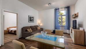A modern living room with a glass-top dining table, a sofa, and a TV on a wooden cabinet. - Apartment 1729/17944 (Istria - Pula), 3000m from the beach (Pula)