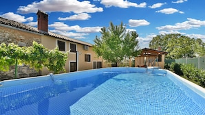 A swimming pool with a tiled deck, a stone wall, and a small building with a tiled roof. - House 1735/17984 (Istria - Galižana), 5000m from the beach (Galižana)