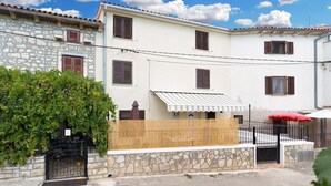 A two-story building with stone and plaster walls, multiple windows with shutters, and a small covered outdoor area with a striped awning. - House 1736/17992 (Istria - Premantura), 600m from the beach (Premantura)