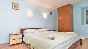 A bedroom with a bed, wooden wardrobe, bedside tables, and wall-mounted lights. - House 1736/17992 (Istria - Premantura), 600m from the beach (Premantura)