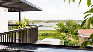 A balcony with a view of a river and greenery.