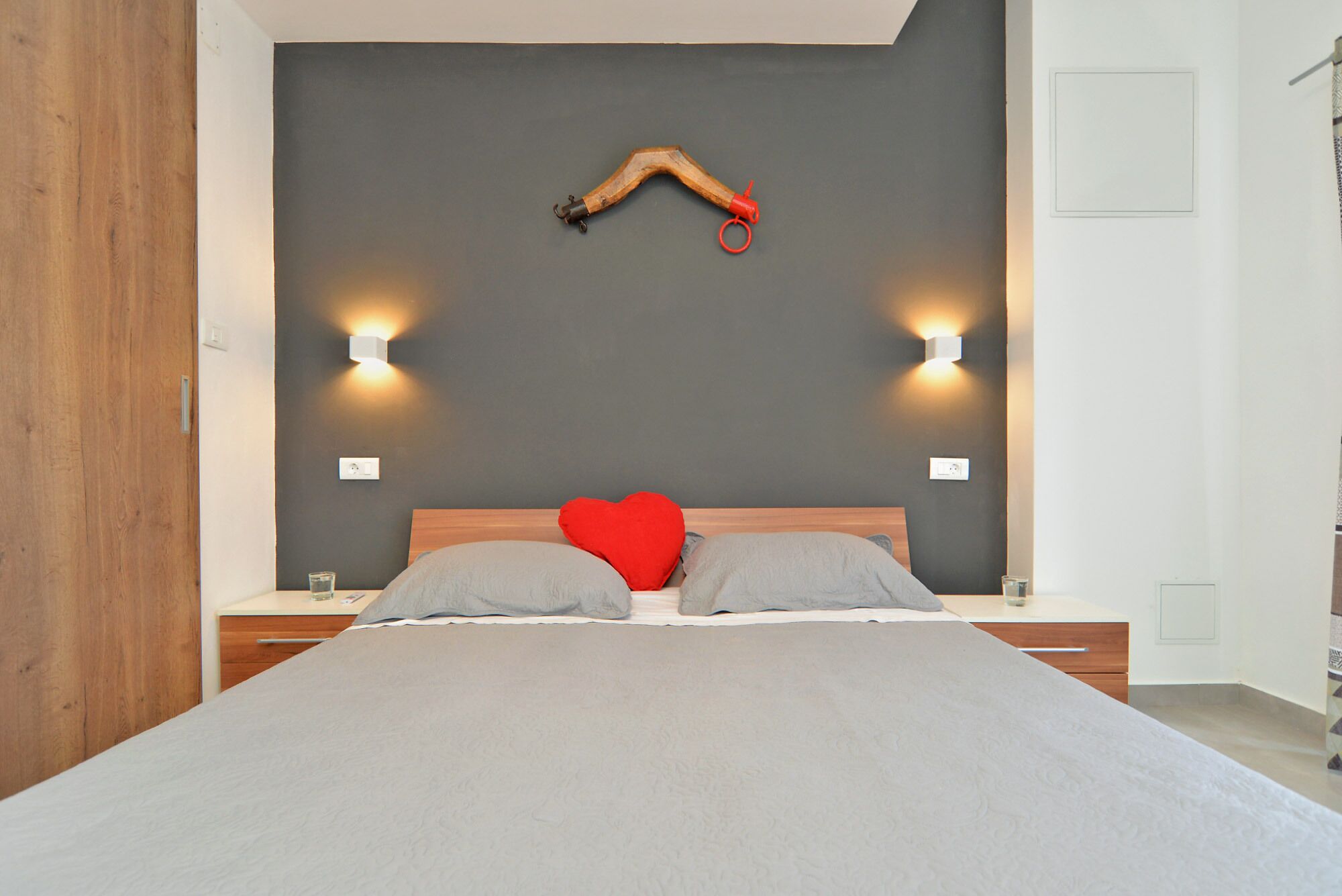 Une chambre à coucher avec un grand lit, deux tables de chevet, une tête de lit en bois et deux lampes fixées au mur.