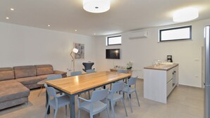 Une cuisine moderne avec une table et des chaises en bois, un four encastré et un petit plan de travail.