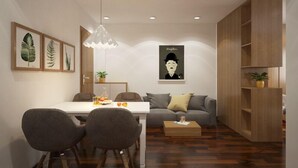 Una sala de estar moderna con comedor, un sofá gris, un mueble de madera y una lámpara colgante.